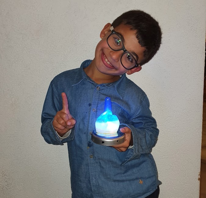 ילד עם יד שעווה מוארת בכחול ולבן