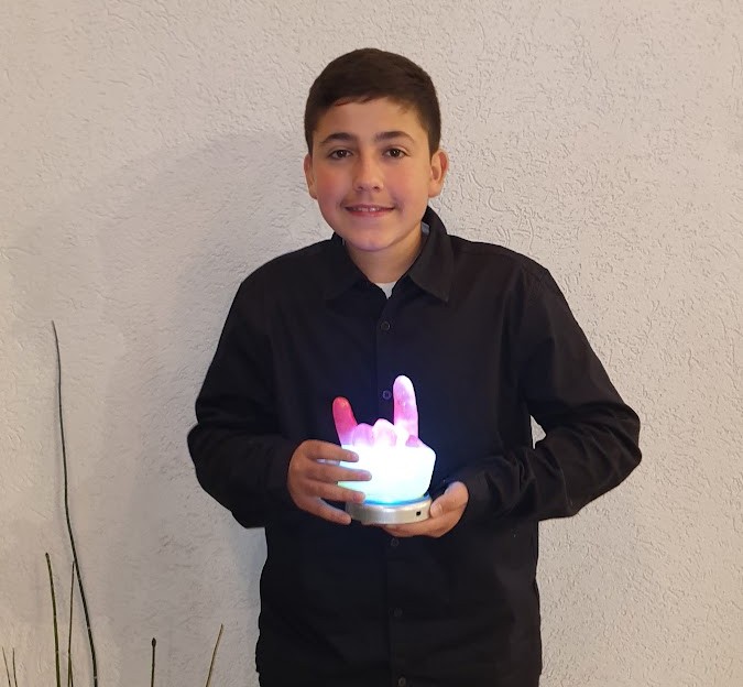 נער מחזיק יד שעווה מוארת בתנוחת רוק