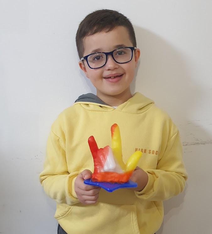 ילד עם יד שעווה בצבעי אדום צהוב ולבן